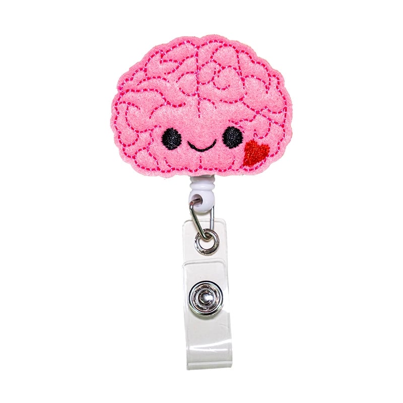 Porta carnet con forma de cerebro, de color rosado, con borde fucsia cosido. Tipo yoyo retráctil. Se conecta mediante un gancho metálico triangular unido a un aro metálico. Desde este aro se extiende un adaptador de color blanco con broche metálico para s. Haga clic para ampliar la imagen