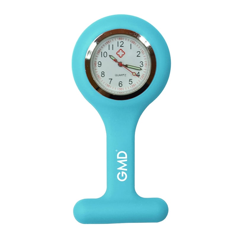 Reloj gmd color azul cielo, con carcasa de silicona en forma de “T” y la marca “GMD”. Fondo blanco con números en la parte superior dispuestos en dos filas: primero números rojos y debajo números negros de mayor tamaño. En el centro tiene una pequeña cruz. Haga clic para ampliar la imagen