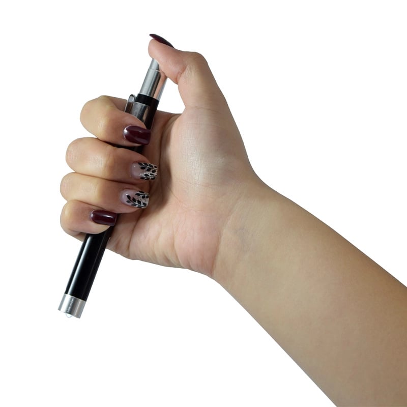 Linterna de diagnóstico premium GMD, tipo bolígrafo, de color negro con acabados plateados en ambos extremos. Sostenida con una mano entre los dedos, con el pulgar apoyado sobre el mecanismo retráctil, el dedo índice sujetando el clip metálico lateral y l. Haga clic para ampliar la imagen