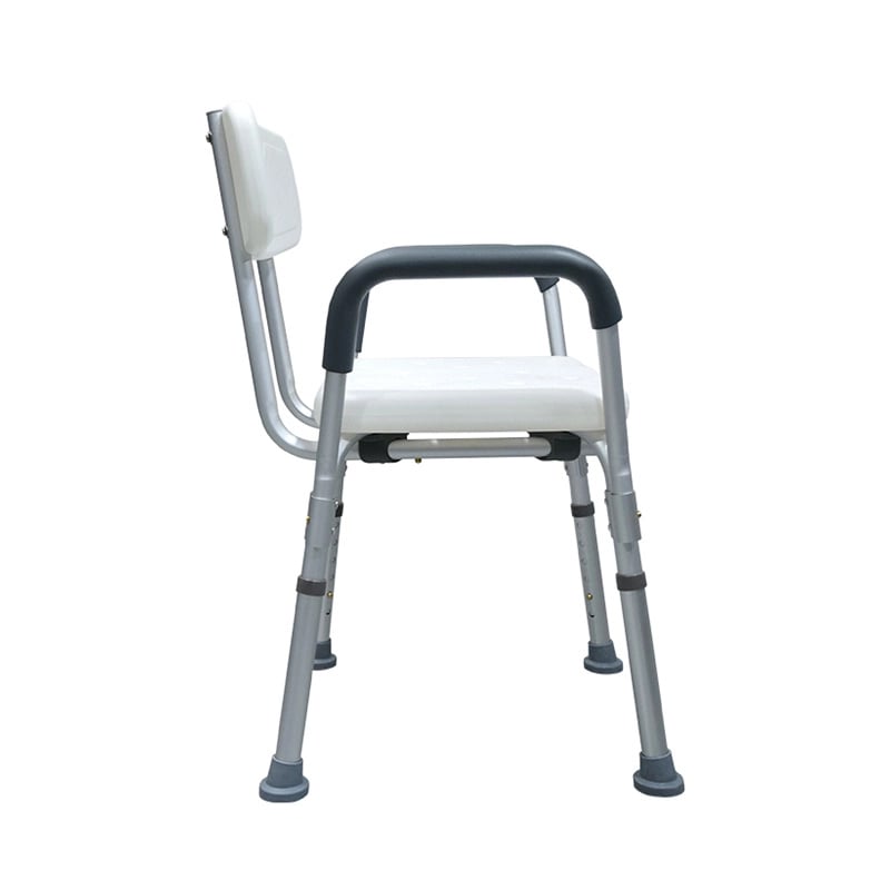Silla para ducha con brazos, vista lateral izquierda, estructura metálica gris. En las patas con pines adaptadores para ajuste de altura y gomas negras antideslizantes, respaldo rectangular blanco con abertura central para el agarre, reposabrazos acolchad. Haga clic para ampliar la imagen