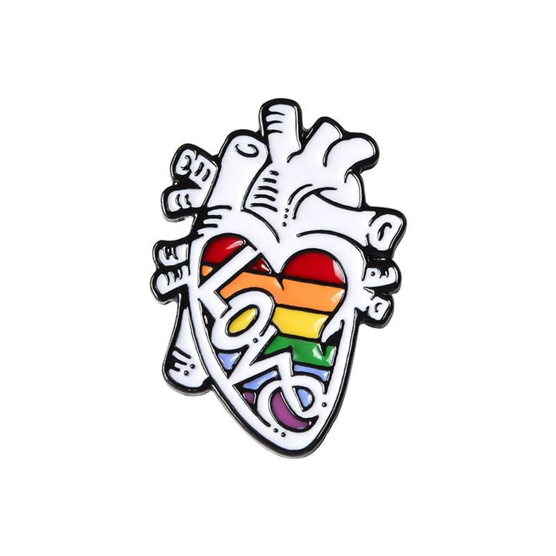 Pin Corazón Arcoiris GMD, fondo blanco, con bordes negros; en el centro franjas rojo, naranja, amarillo, verde, azul y morado, con la palabra “LOVE” encima.