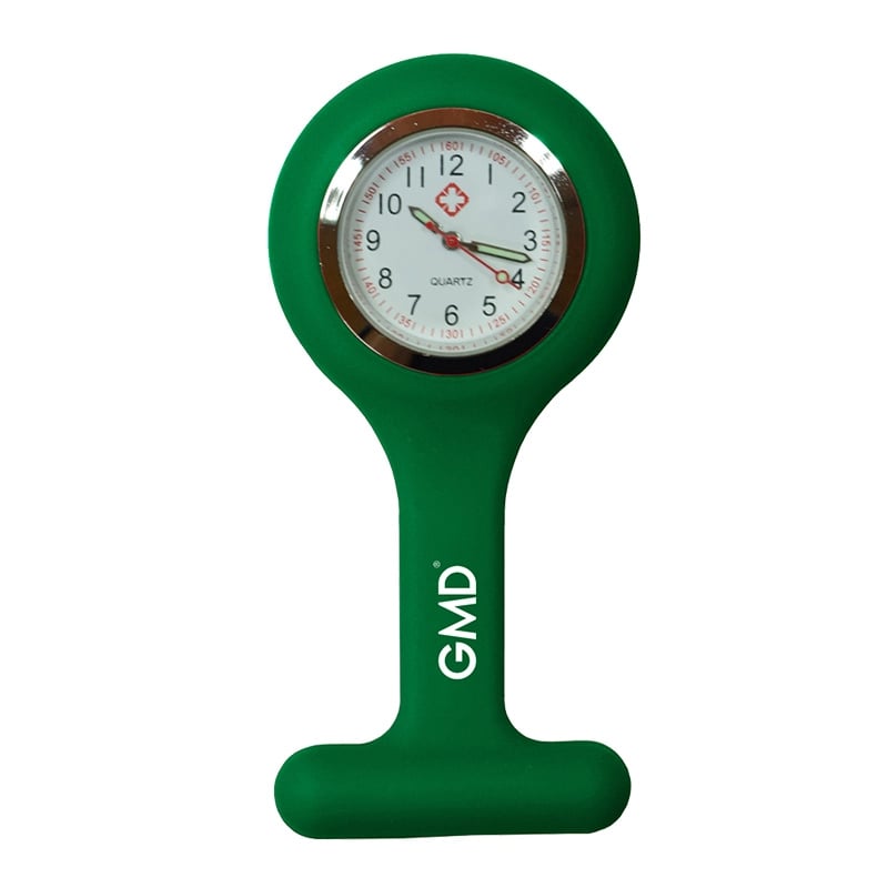Reloj gmd color verde oscuro, con carcasa de silicona en forma de “T” y la marca “GMD”. Fondo blanco con números en la parte superior dispuestos en dos filas: primero números rojos y debajo números negros de mayor tamaño. En el centro tiene una pequeña cr. Haga clic para ampliar la imagen