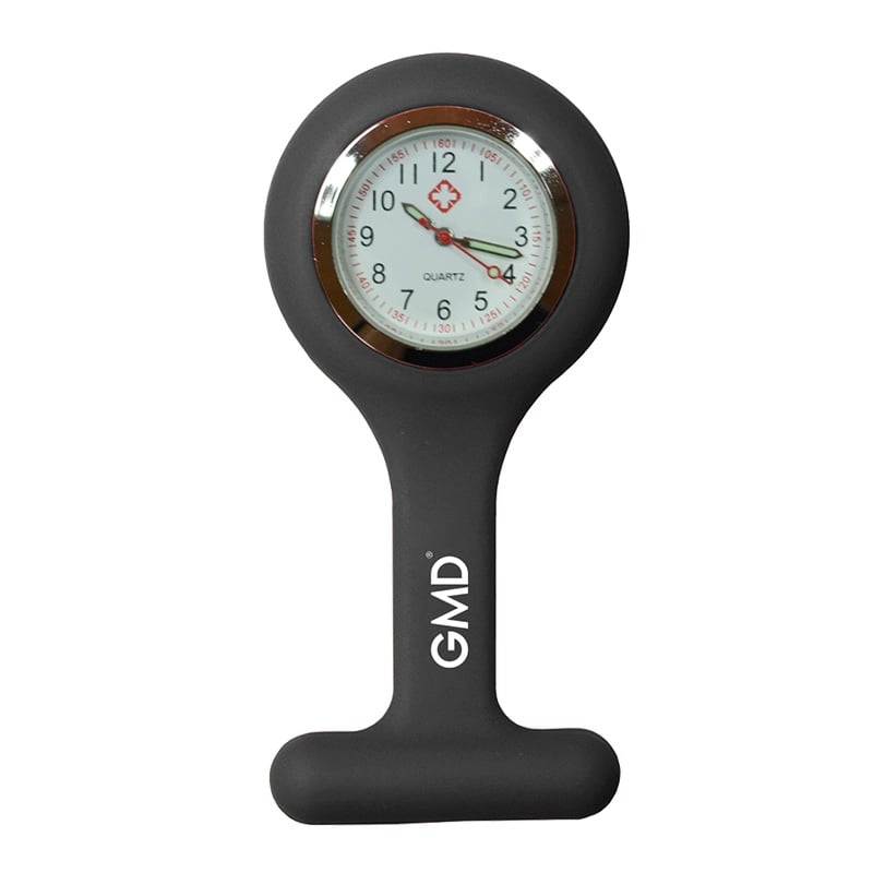 Reloj gmd color gris, con carcasa de silicona en forma de “T” y la marca “GMD”. Fondo blanco con números en la parte superior dispuestos en dos filas: primero números rojos y debajo números negros de mayor tamaño. En el centro tiene una pequeña cruz roja . Haga clic para ampliar la imagen